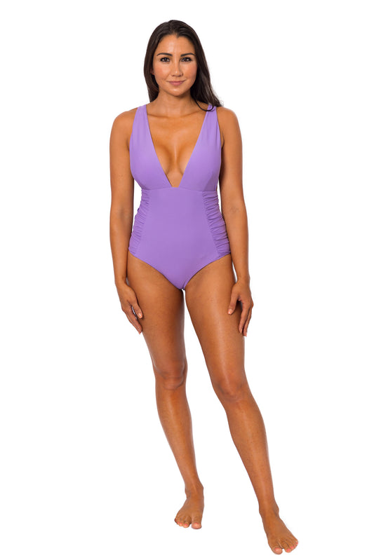 Woman's one-piece bathing suit in periwinkle Purple with Deep V neckline, ruching on the side, adjustable straps and cheeky to moderate coverage